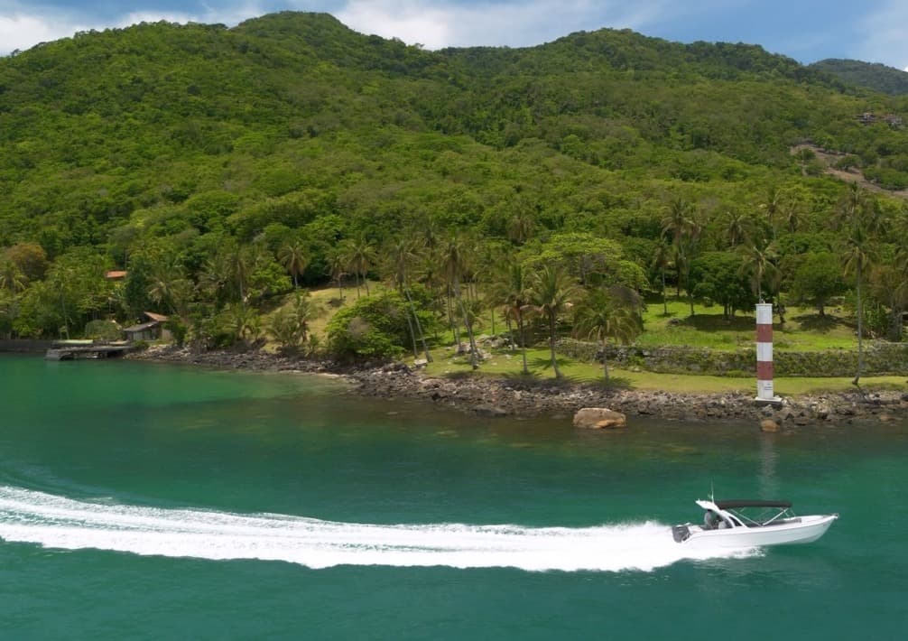 Lancha navegando junto à costa verde de Ilhabela