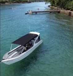 Lancha navegando próxima à costa verde de Ilhabela